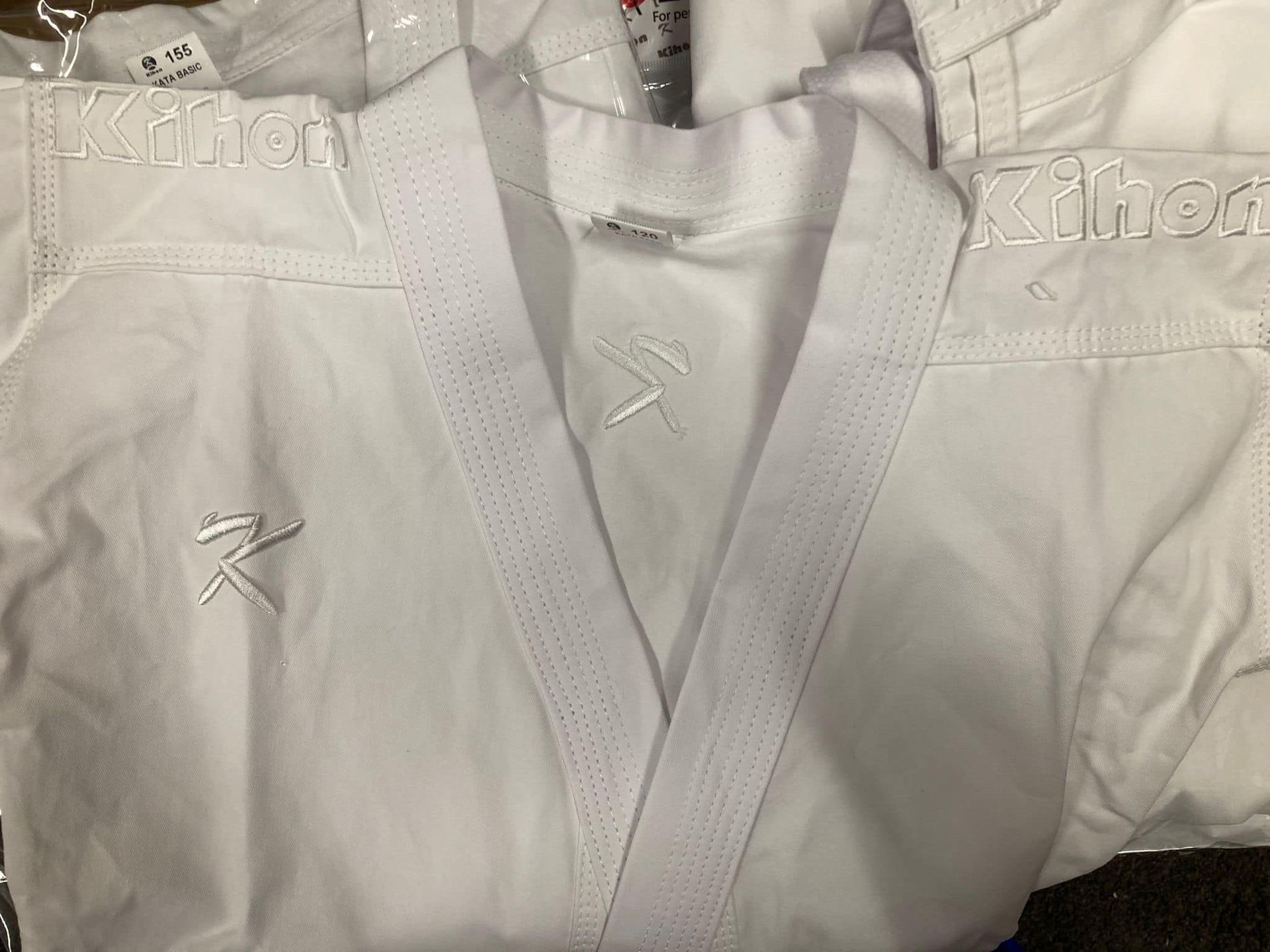 Close-up of a white martial arts gi with embroidered logos, neatly folded.